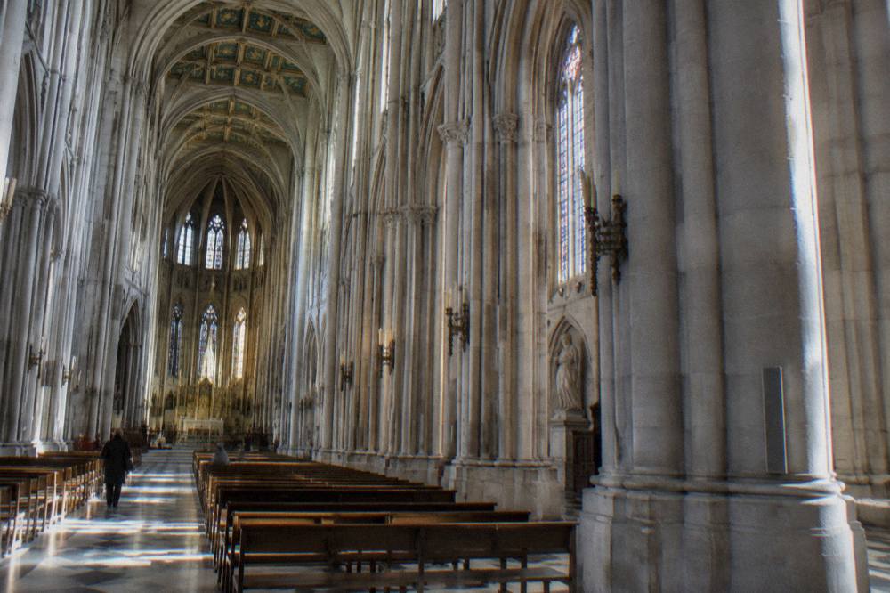 Sunlit interior of the cathedral nave with rows of columns and coloured ceiling decoration