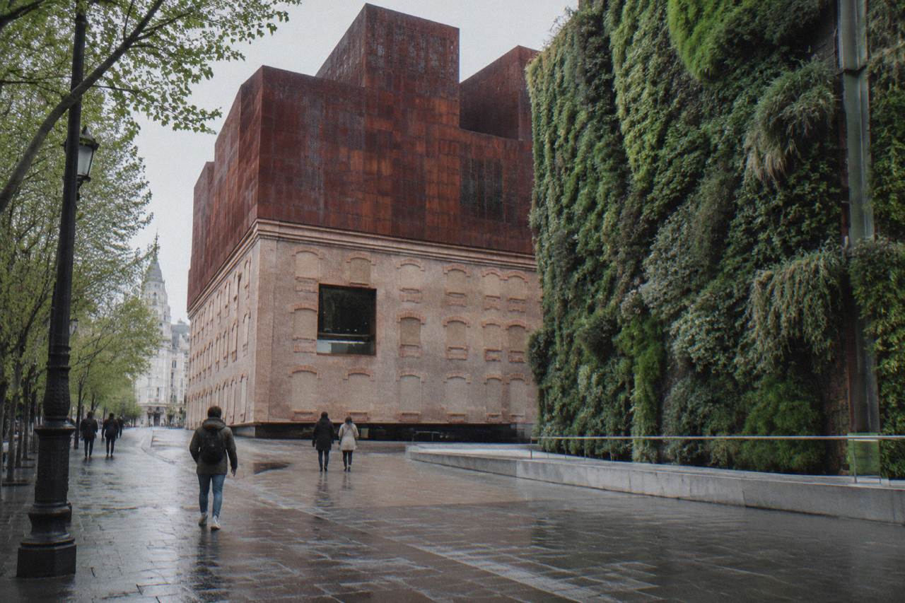 CaixaForum Madrid brick and rusted-iron building with the green vertical garden wall beside the street
