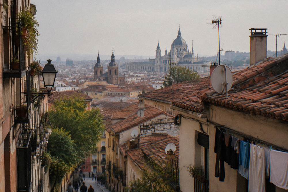 View over Madrid rooftops from a La Latina street, with church towers and palace architecture in the distance