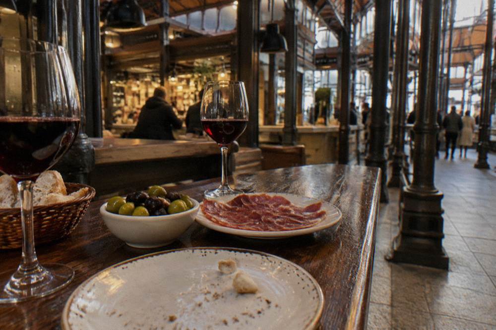 Tapas plates and glasses of wine on a wooden bar counter in a Madrid taberna