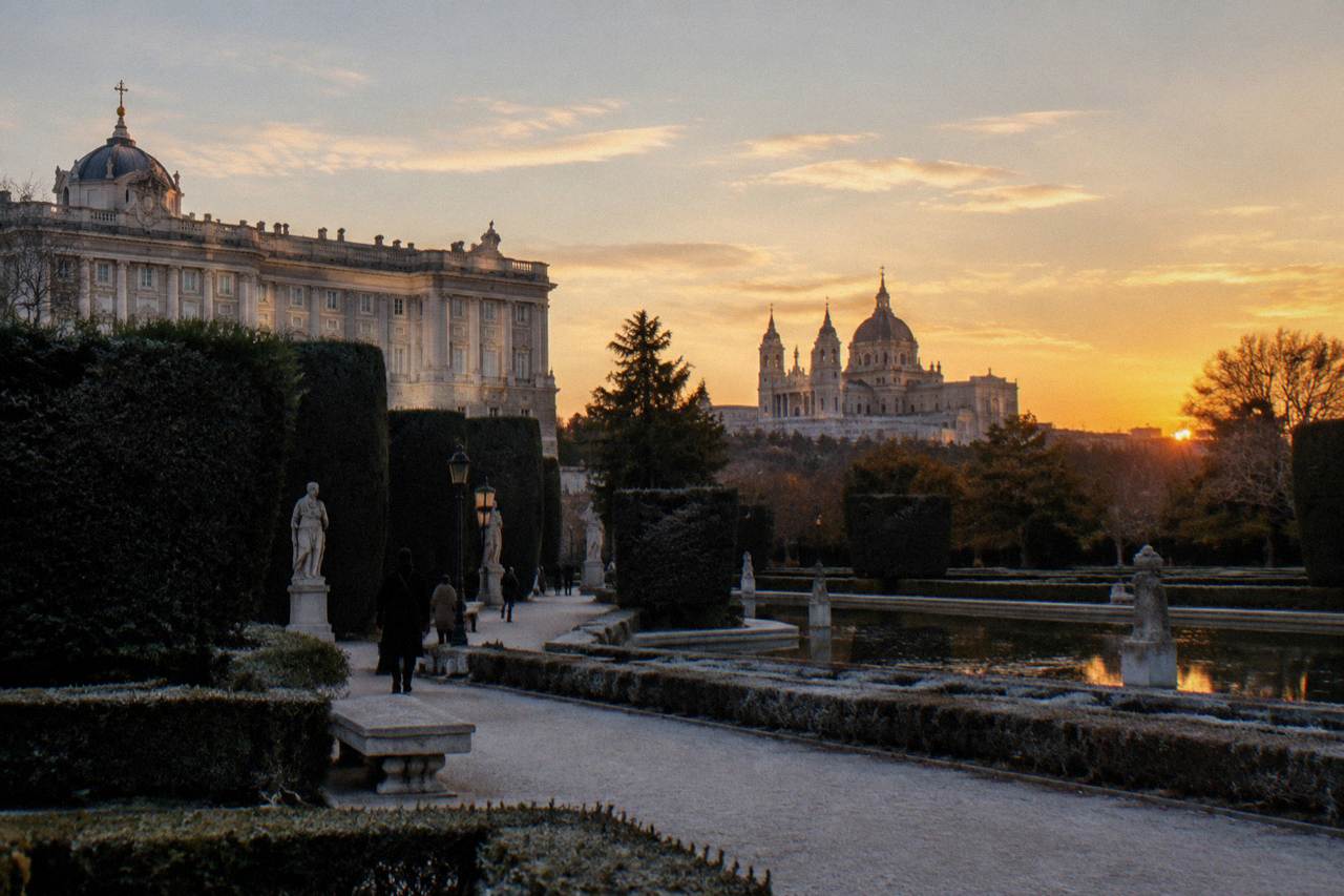Wide view of Madrid rooftops at sunset with the Royal Palace and Almudena Cathedral in the distance