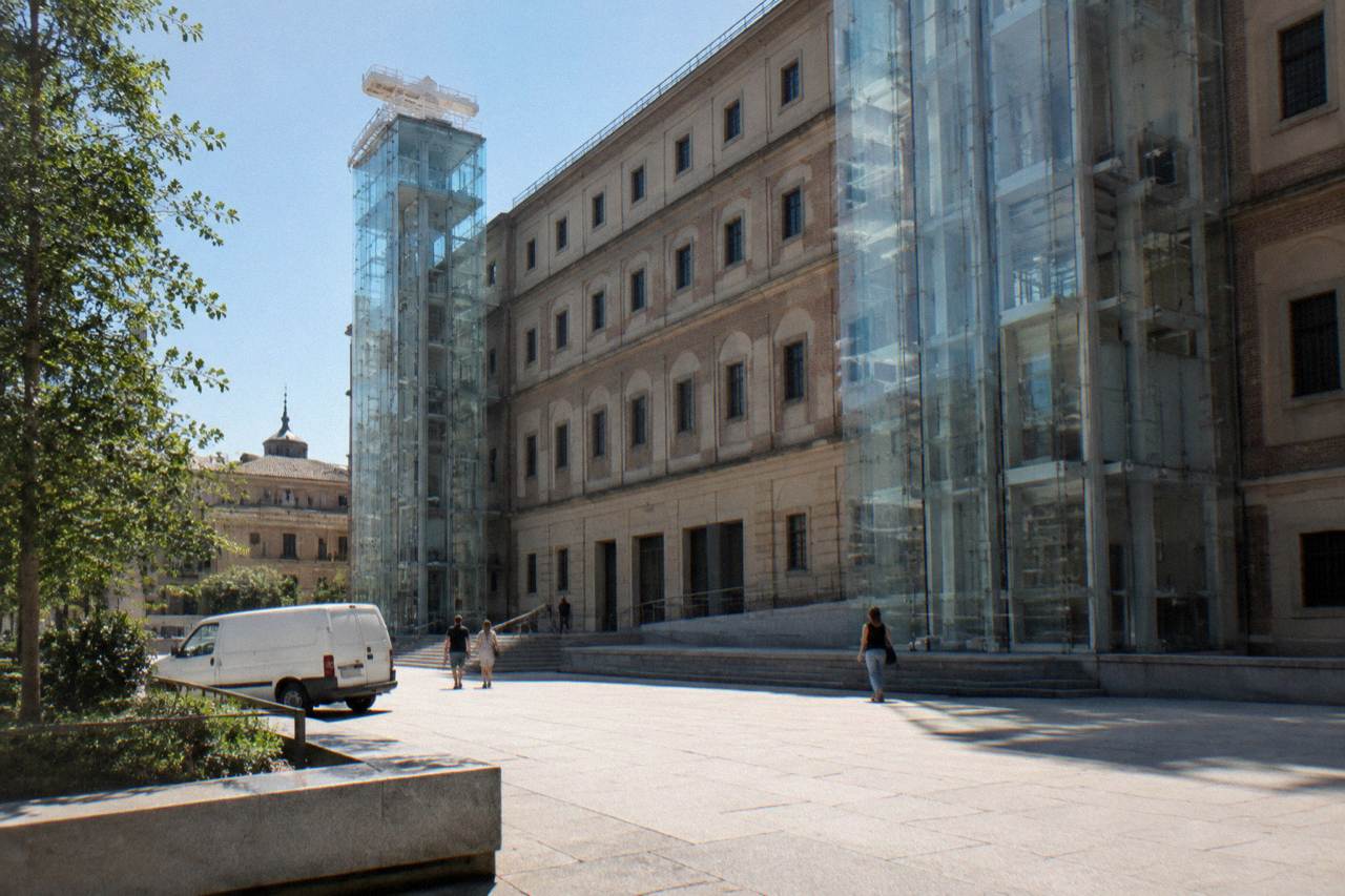 Facade of the Reina Sofia Museum in Madrid with glass elevator towers beside the old hospital building