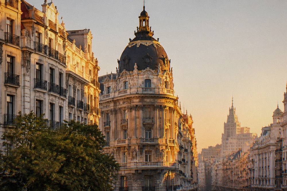 View from a rooftop terrace across Gran Vía toward the Bank of Spain dome at golden hour
