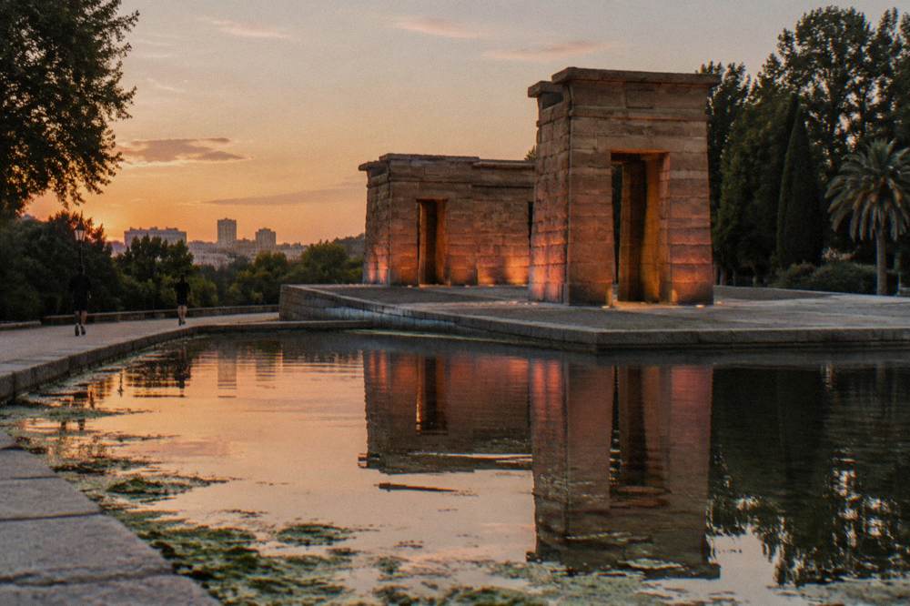 Ancient Egyptian stone temple on a raised platform in a Madrid park at sunset