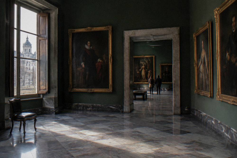 Museum gallery interior with paintings on dark walls and polished stone floor