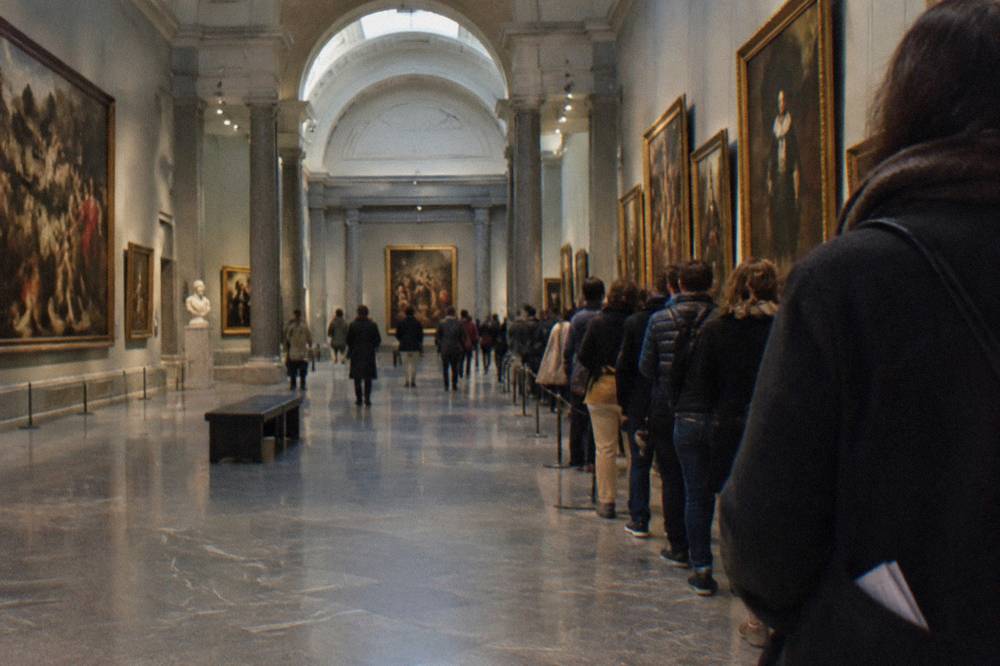 Grand gallery with marble floors and classical paintings hung in rows