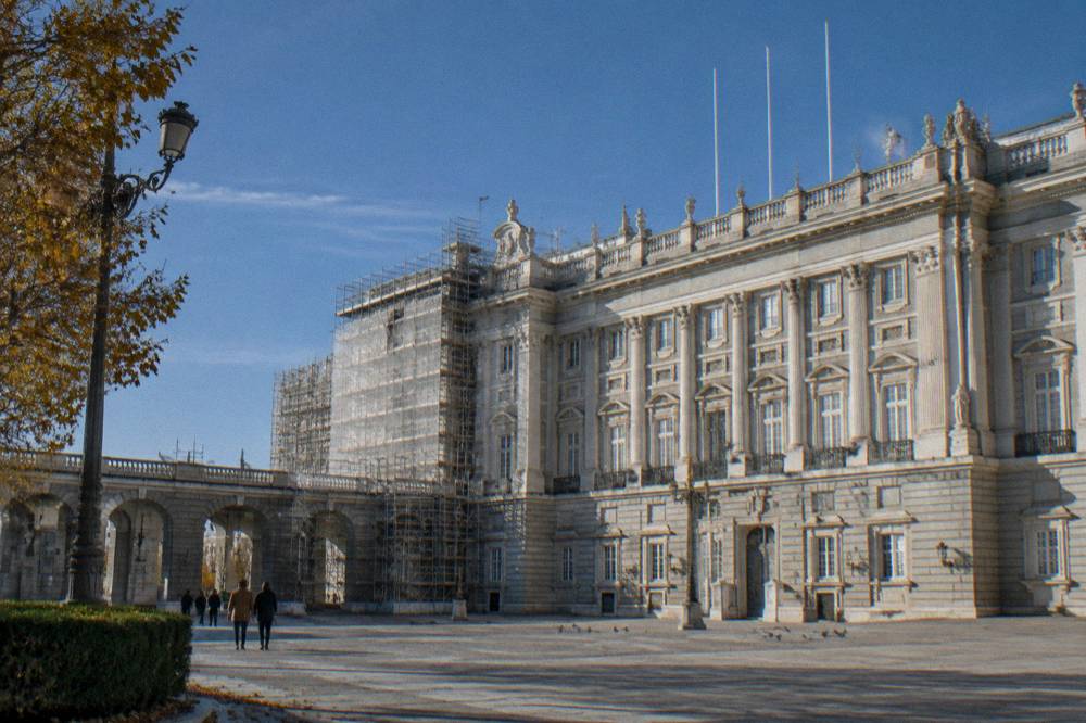 Royal palace facade with classical architecture and flagpoles under a clear sky