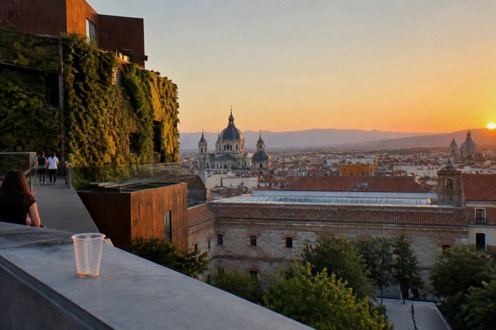 Rooftop view over Madrid skyline at sunset with distant mountains