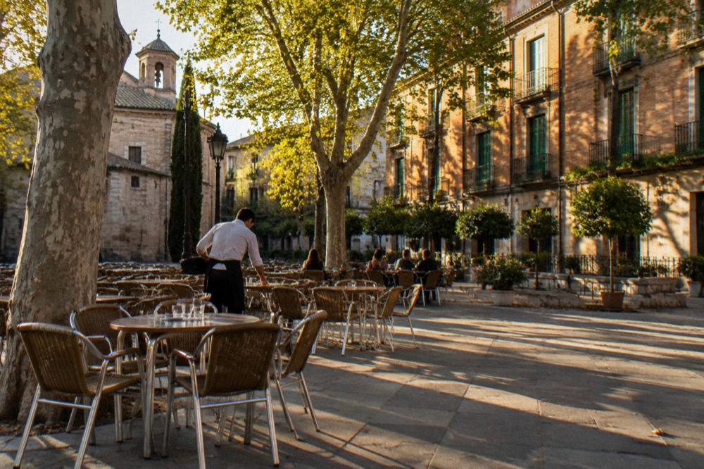 Golden late-afternoon light on a Madrid plaza with café tables