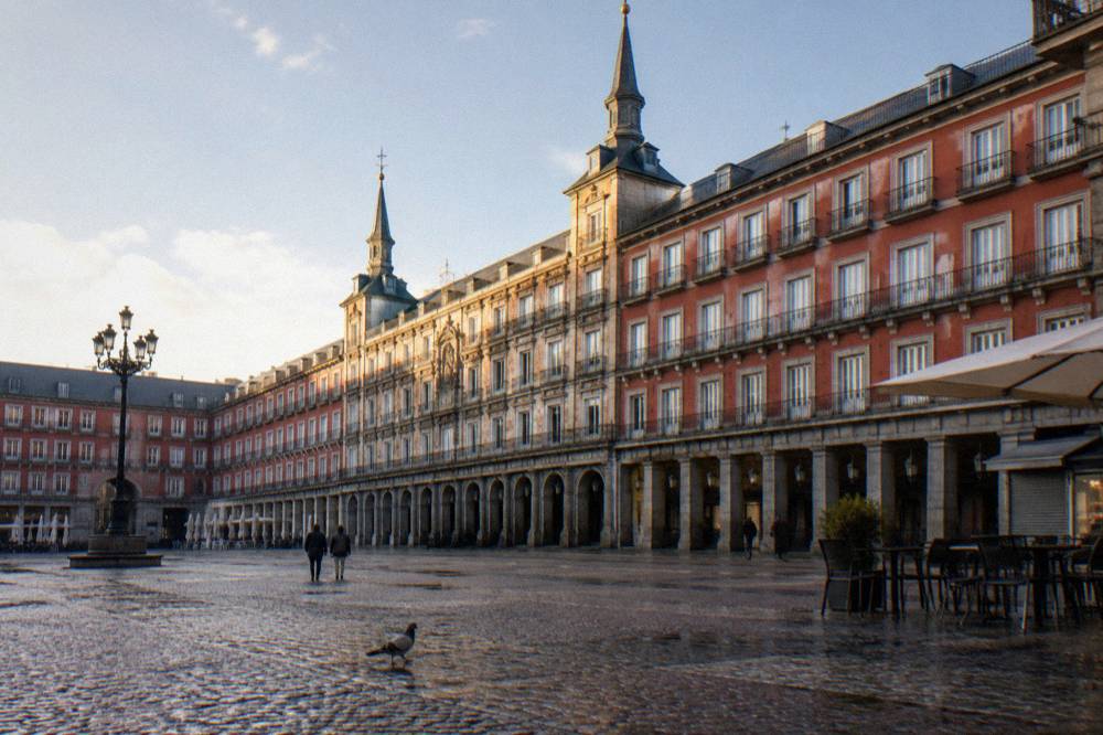 Baroque stone facade of a grand enclosed square in Madrid with balconies and slate spires