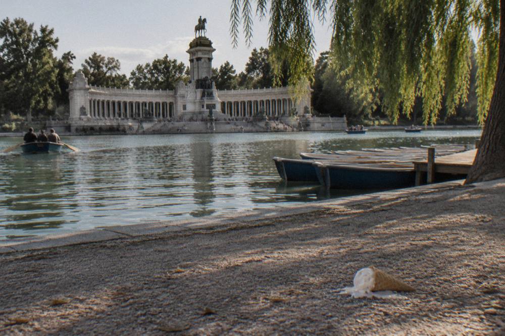 Large ornamental lake in a Madrid park with a stone monument colonnade behind it