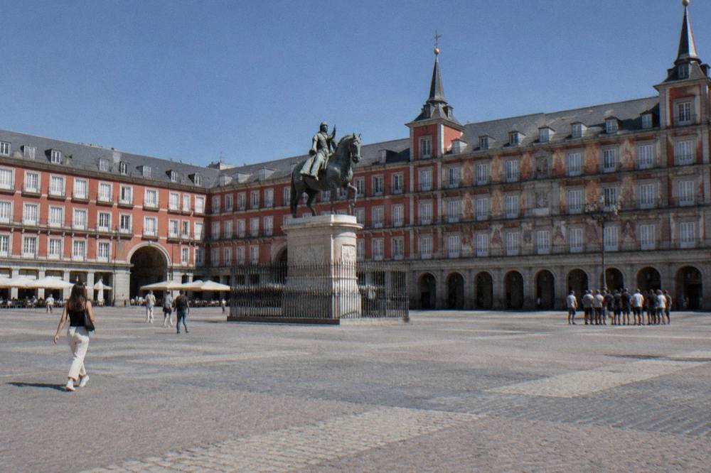 Plaza Mayor in Madrid with its red facades and the equestrian statue under a clear sky