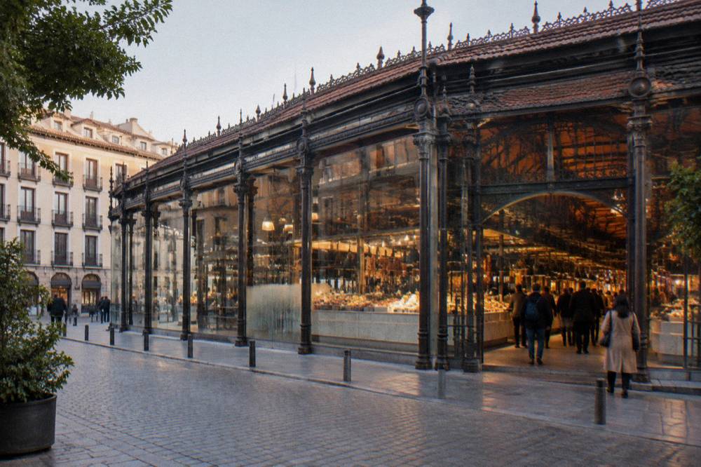 Mercado de San Miguel in Madrid with its glass walls and food stalls visible from the square outside