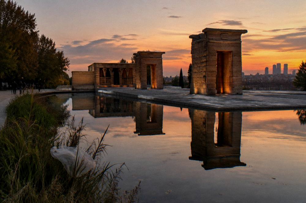 Templo de Debod at sunset with reflections in the water basin and the Madrid skyline behind