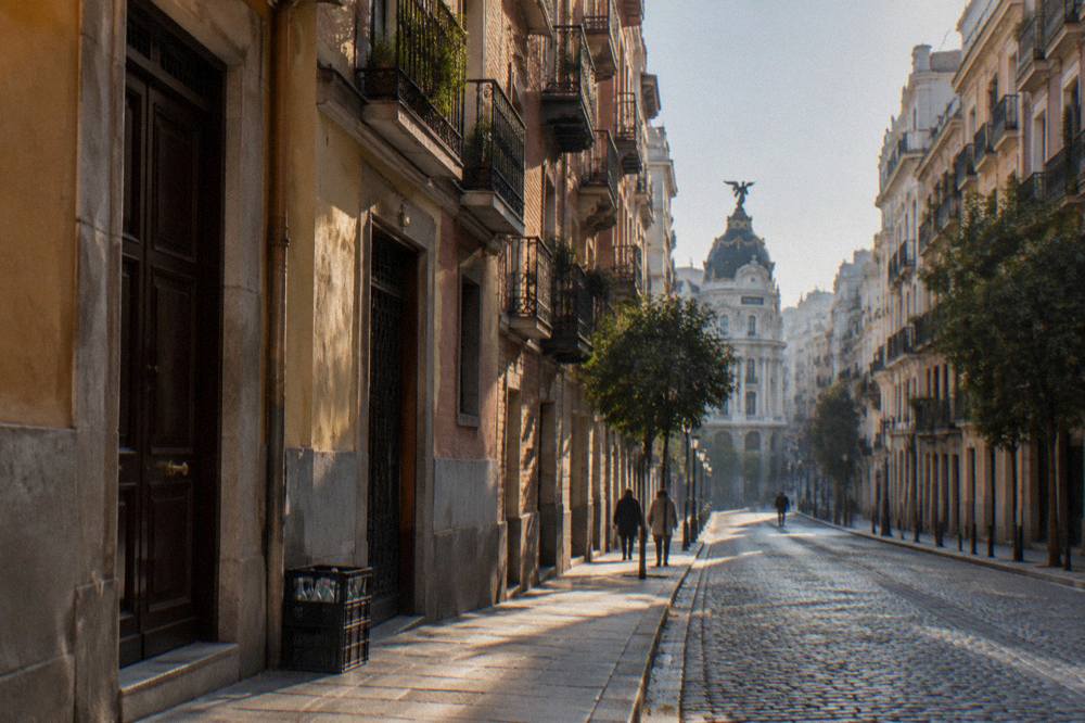 Narrow cobblestone street in old Madrid with ochre buildings and hanging balconies