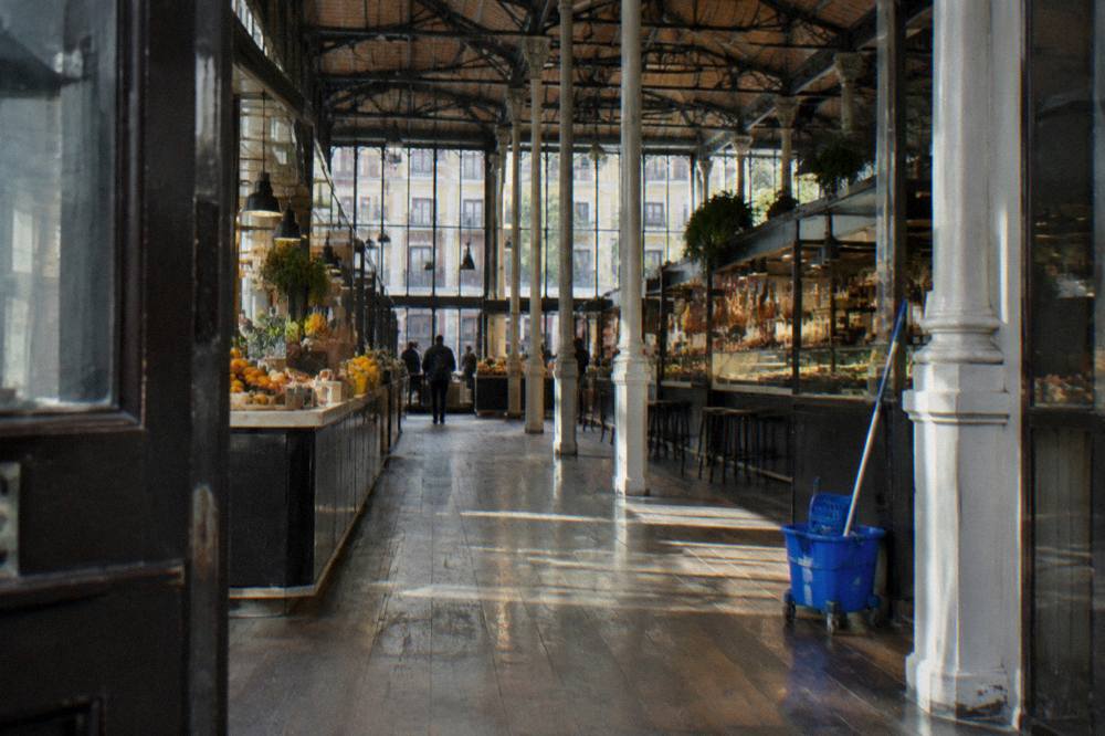 Interior of an iron and glass market hall with food stalls and standing tables