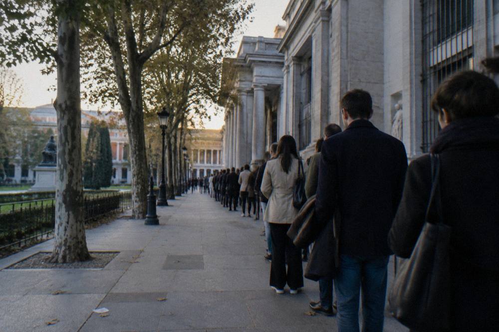 Long queue of visitors waiting outside the Prado Museum entrance in early evening light