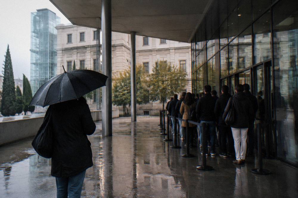 The queue sheltering under the Reina Sofía entrance canopy in late afternoon light