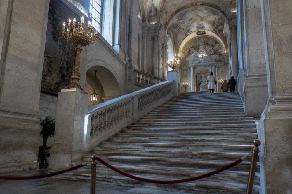 The grand staircase inside the Royal Palace of Madrid with its marble steps and frescoed ceiling