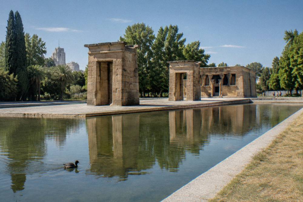 Sandstone temple walls with carved details rising above a still pool