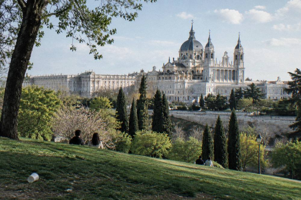 Madrid cathedral and royal palace seen from a green park slope